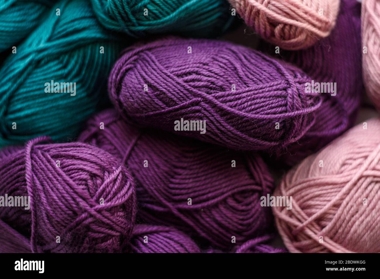 Many colored knitting wool balls background. Green, purple and pink. Pattern. Stock Photo