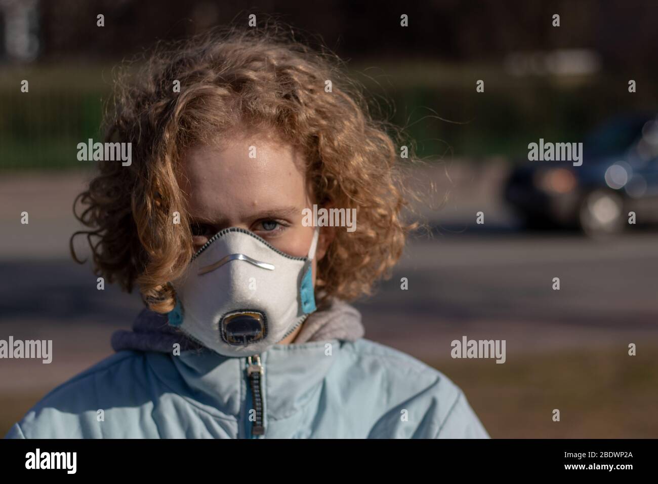 Yound girl with blonde hair with serious face with protective medical mask. Angry look. Ecology and climate disaster concept. Copy space Stock Photo
