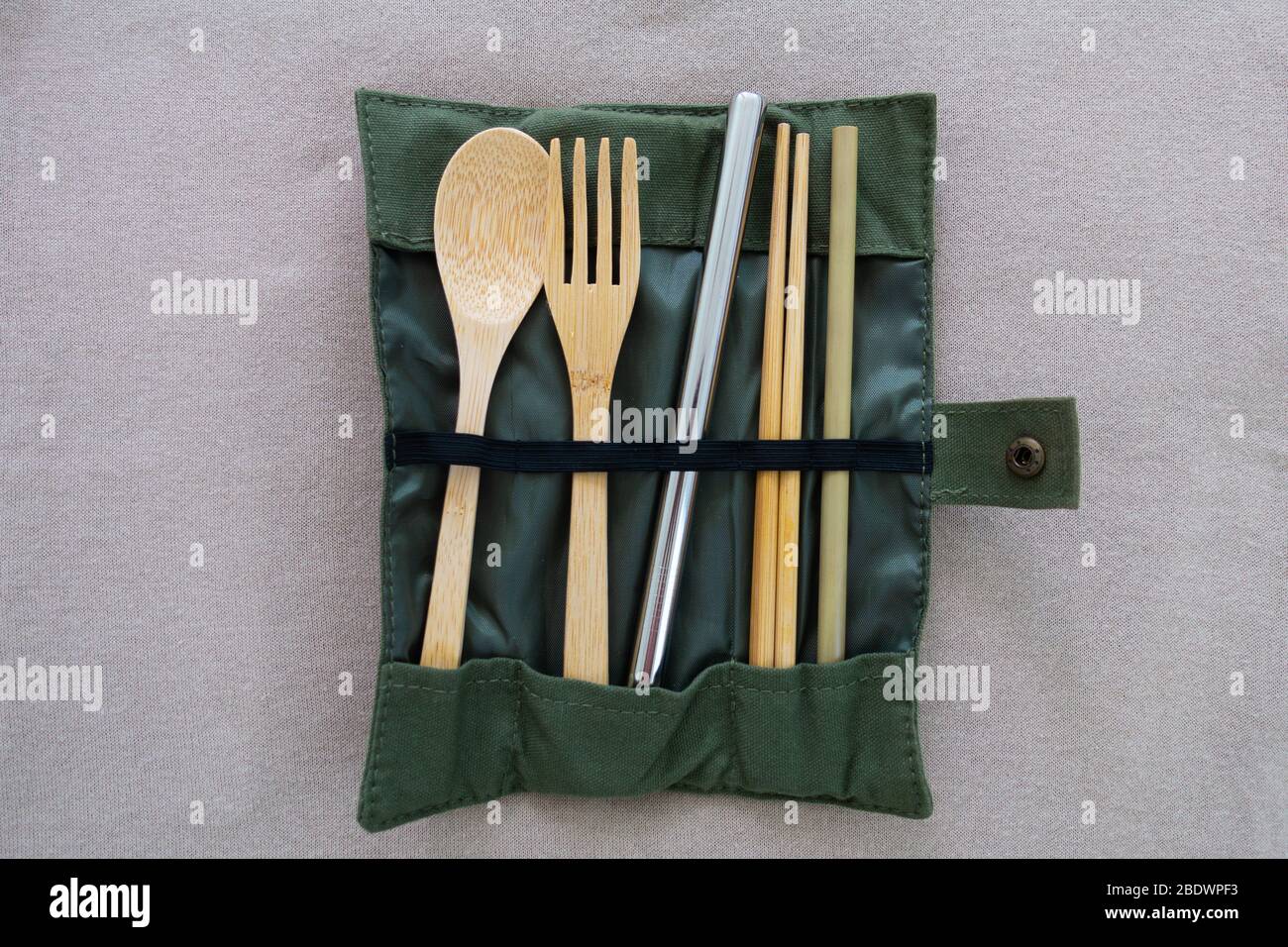 Reusable and environmental friendly utensils include bamboo spoon, fork, chopsticks, small straw, one big stainless steel straw in a folded cloth bag. Stock Photo