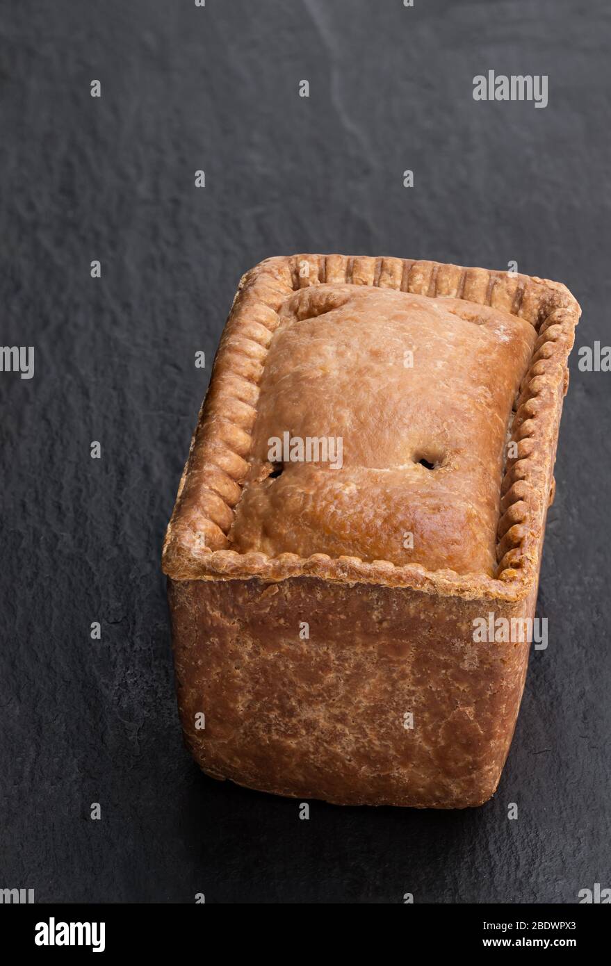 Traditional English savoury gala egg pork pie on black stone background