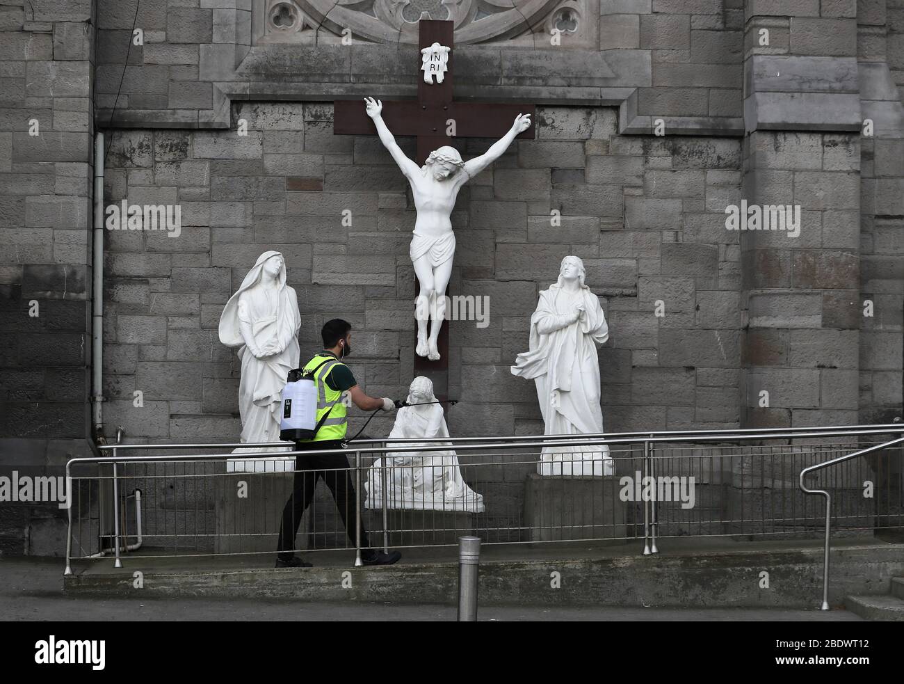 A man sprays disinfectant at a statue of the crucifixion of Jesus outside St. Mary of the Angels church in Dublin, on Good Friday, the Christian holiday commemorating the crucifixion of Jesus and his death at Calvary. Stock Photo