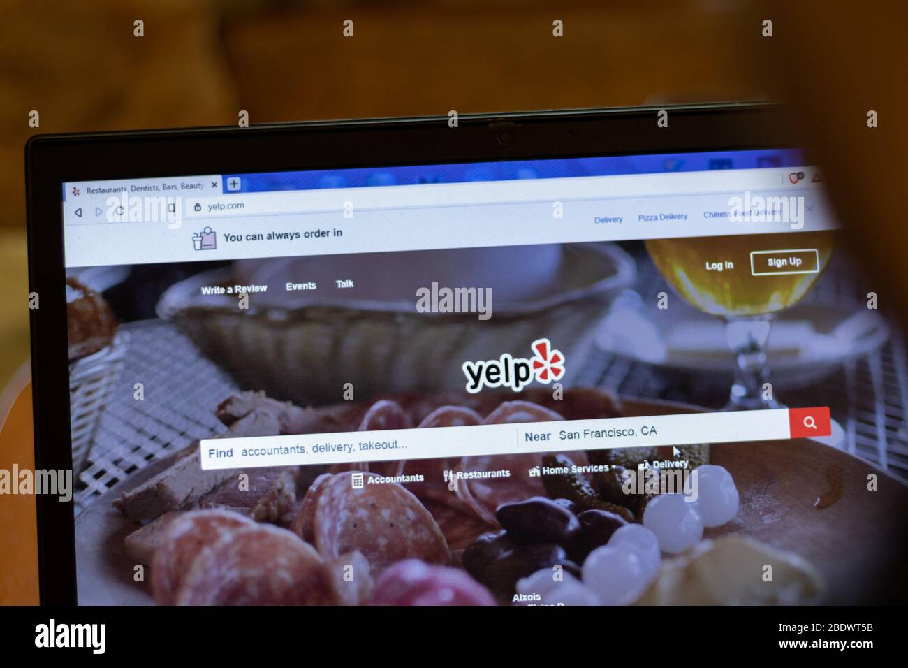 New York, USA - 9 April 2020: Yelp website on laptop screen close up. Man using service on display, blurry background, Illustrative Editorial Stock Photo