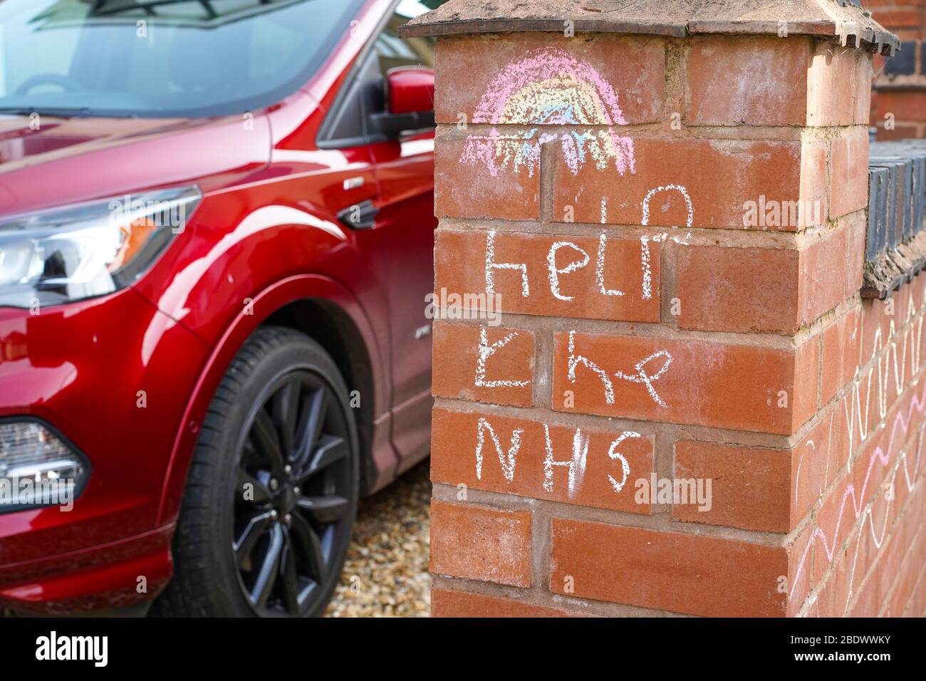 Kidderminster, UK. 10th April, 2020. Following a third Thursday evening where the UK nation comes together to Clap For Our Carers, Clap For Our NHS, a new message appears in a UK garden showing how children too are expressing their understanding and appreciation. A colourful rainbow and simple chalk message, Help The NHS, are lovingly drawn on a front garden wall for pedestrians to see as they pass in the street for their daily exercise. Credit: Lee Hudson/Alamy Live News Stock Photo