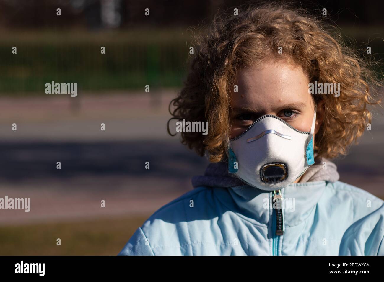 Beautiful young girl with a serious face looks at the camera. The concept of environmental issues and pollution. Copy space on blurry background Stock Photo