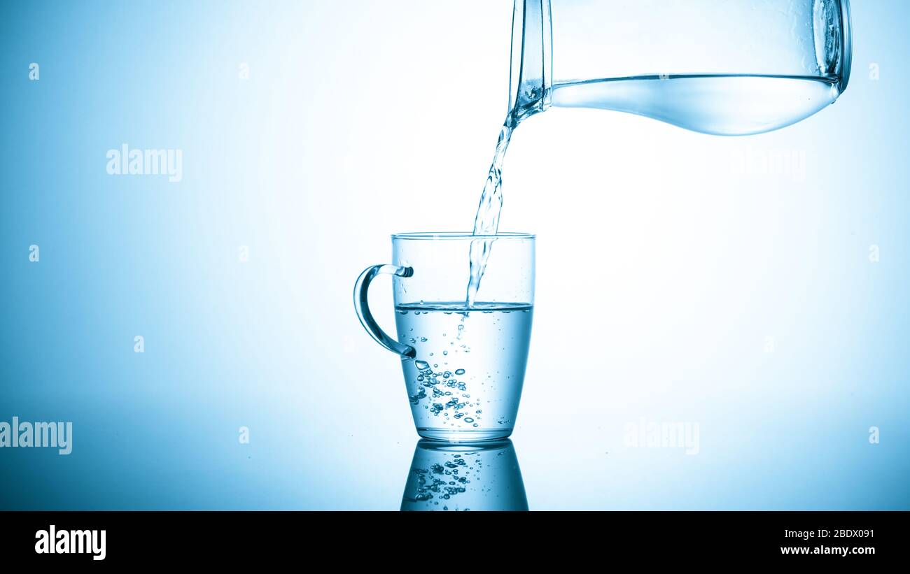 https://c8.alamy.com/comp/2BDX091/filling-a-glass-with-water-from-a-jug-on-a-blue-background-2BDX091.jpg