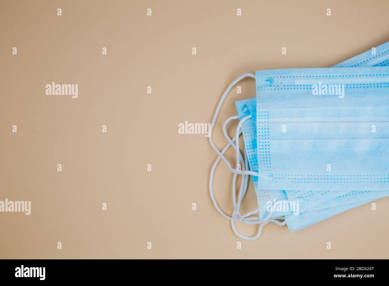 Medical protective mask on a beige background. A disposable surgical face mask closes the mouth