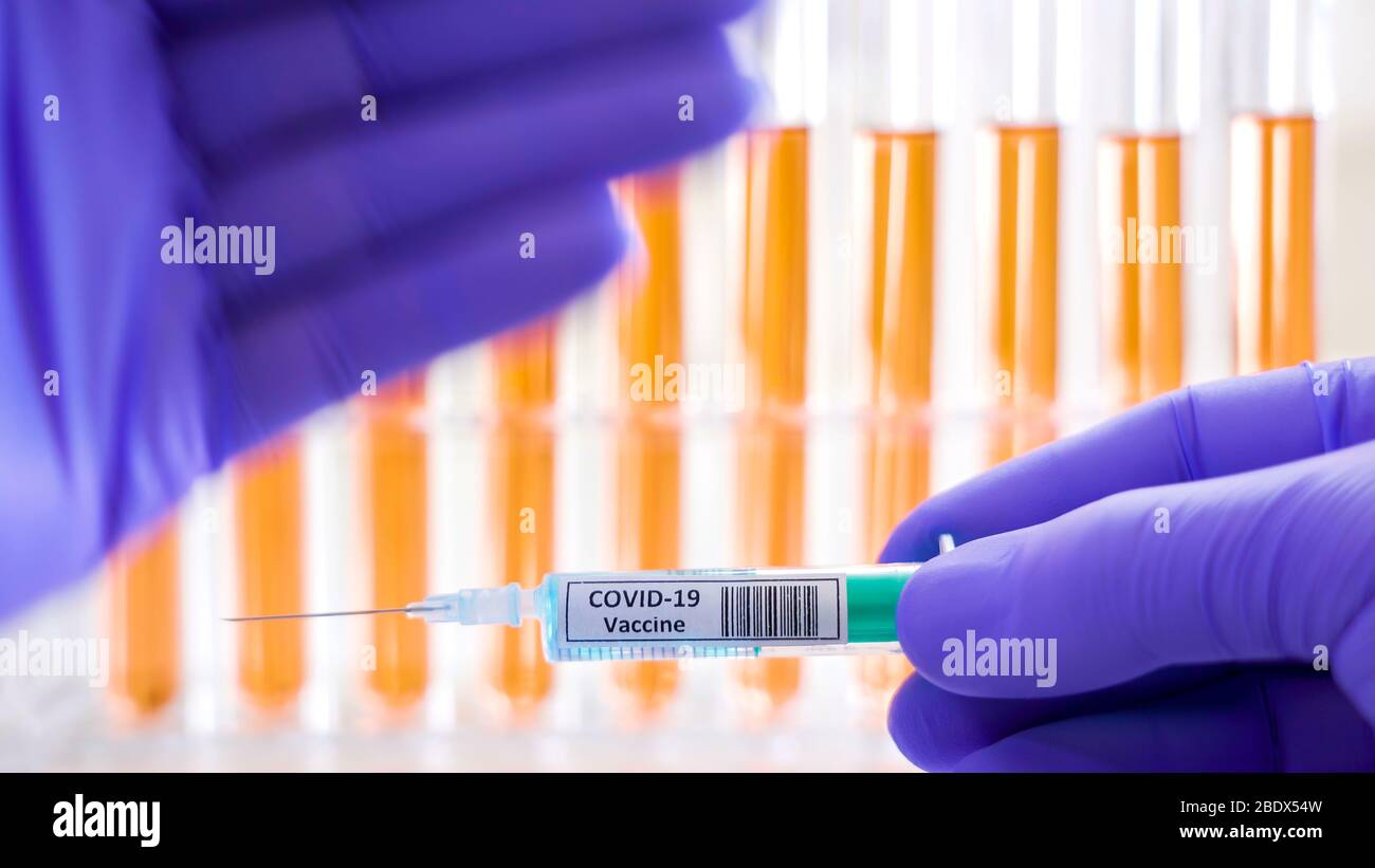 The Covid-19 vaccine for coronavirus being held by the lab doctor and the test tubes on the back Stock Photo