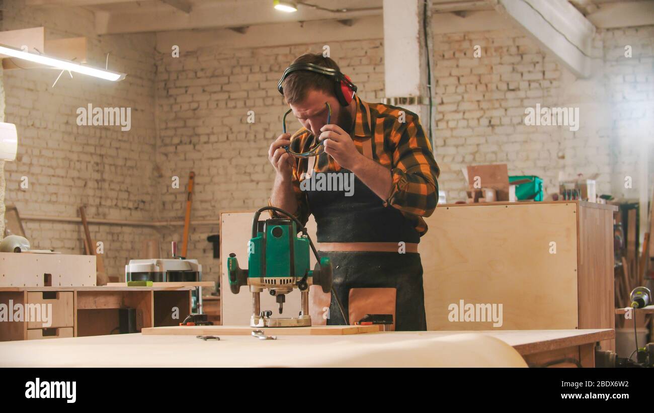 Bearded man worker putting on protective glasses. Mid shot Stock Photo