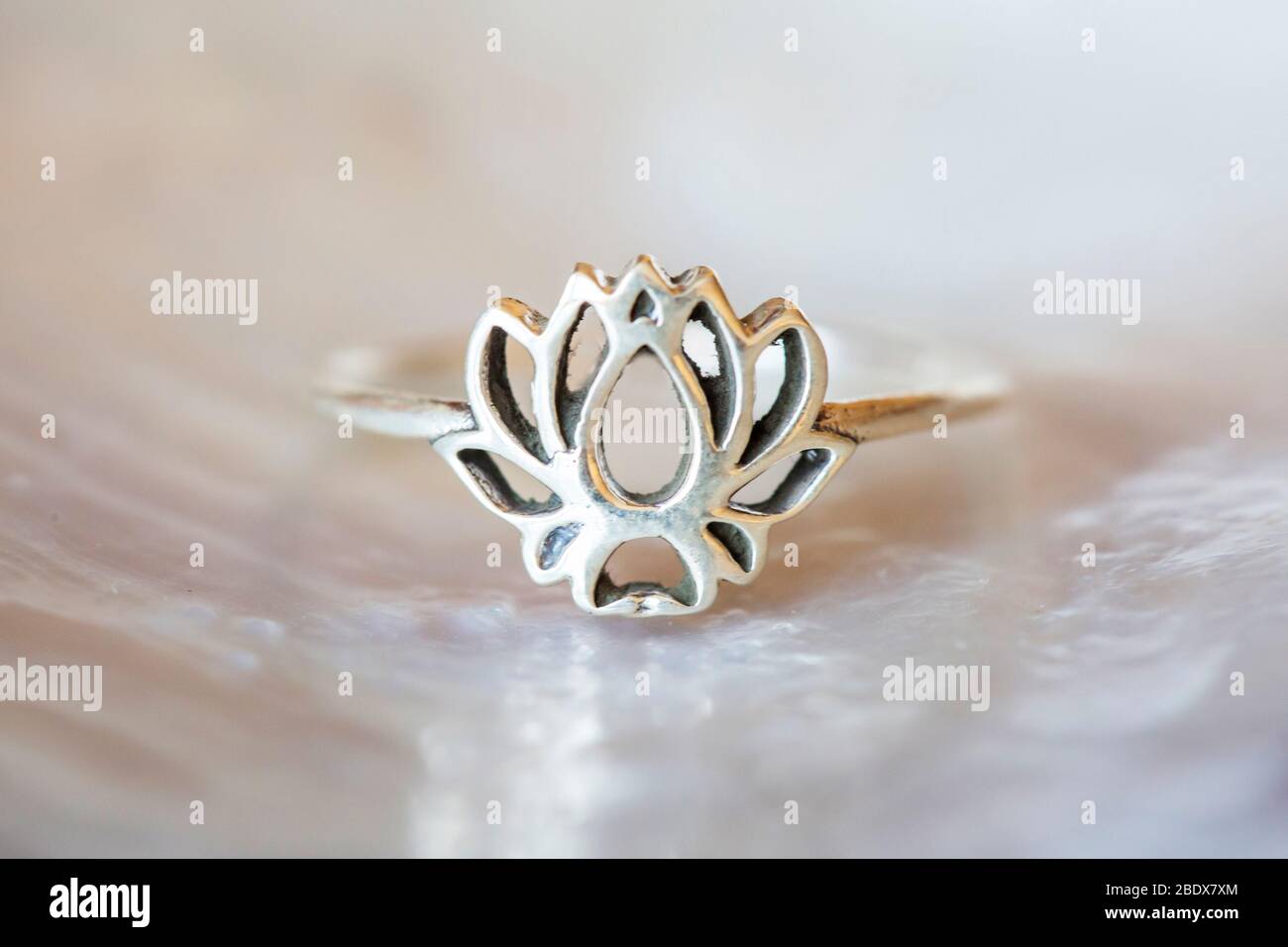 Silver ring tiny jewelry piece on white pearl background in the shape of lotus Stock Photo