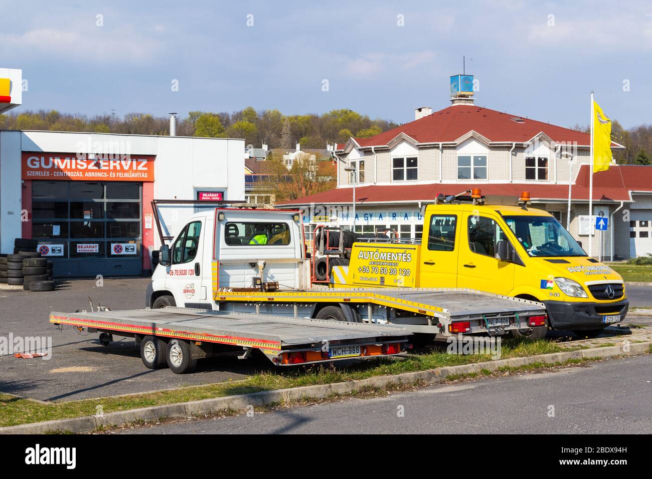 Tow truck trucks and trailer parked near tire tyre service (gumiszerviz) and Hungarian car club (magyar autoklub) building, Sopron, Hungary Stock Photo