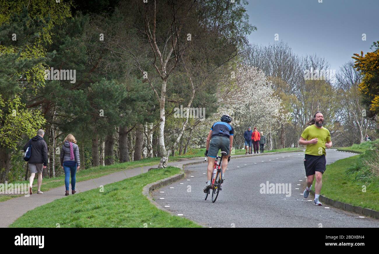 Fairly busy Holyrood Park, Edinburgh, Scotland, UK. 10th April 2020. Pictured: Families walking cyclists puffing up the sloping road which is actually closed to vehicles because of the annual toad migration and joggers on pavements and roads,. How safe the proximity to pedestrians is when the photographer witnessed one runner and one cyclist spitting on the grass border. Credit: Arch White/ Alamy Live News. Stock Photo