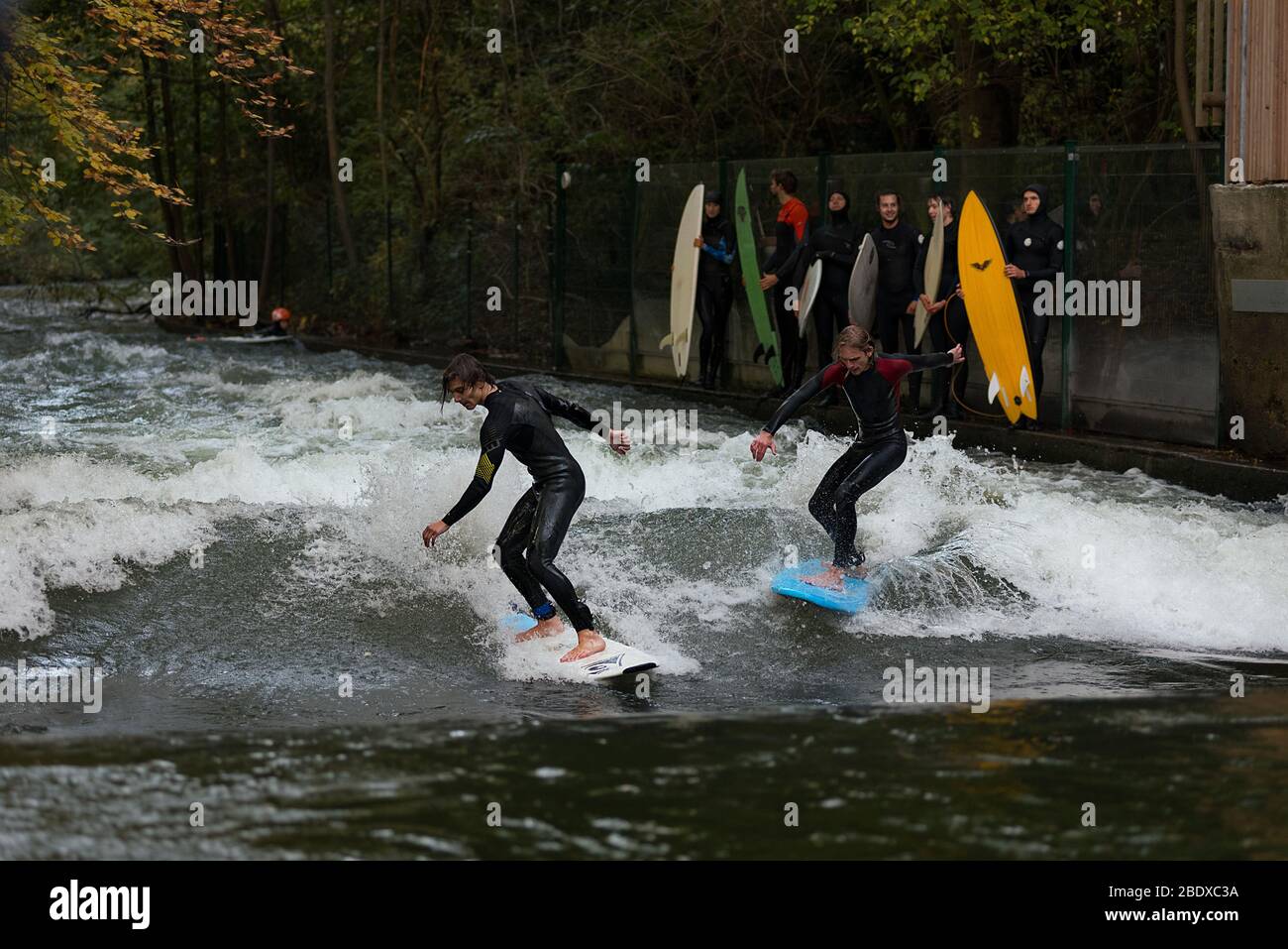Surfers at the E2 Kleine Eisbachwelle  River Surfing spot at Munich, Germany on the river Eisbach. Stock Photo