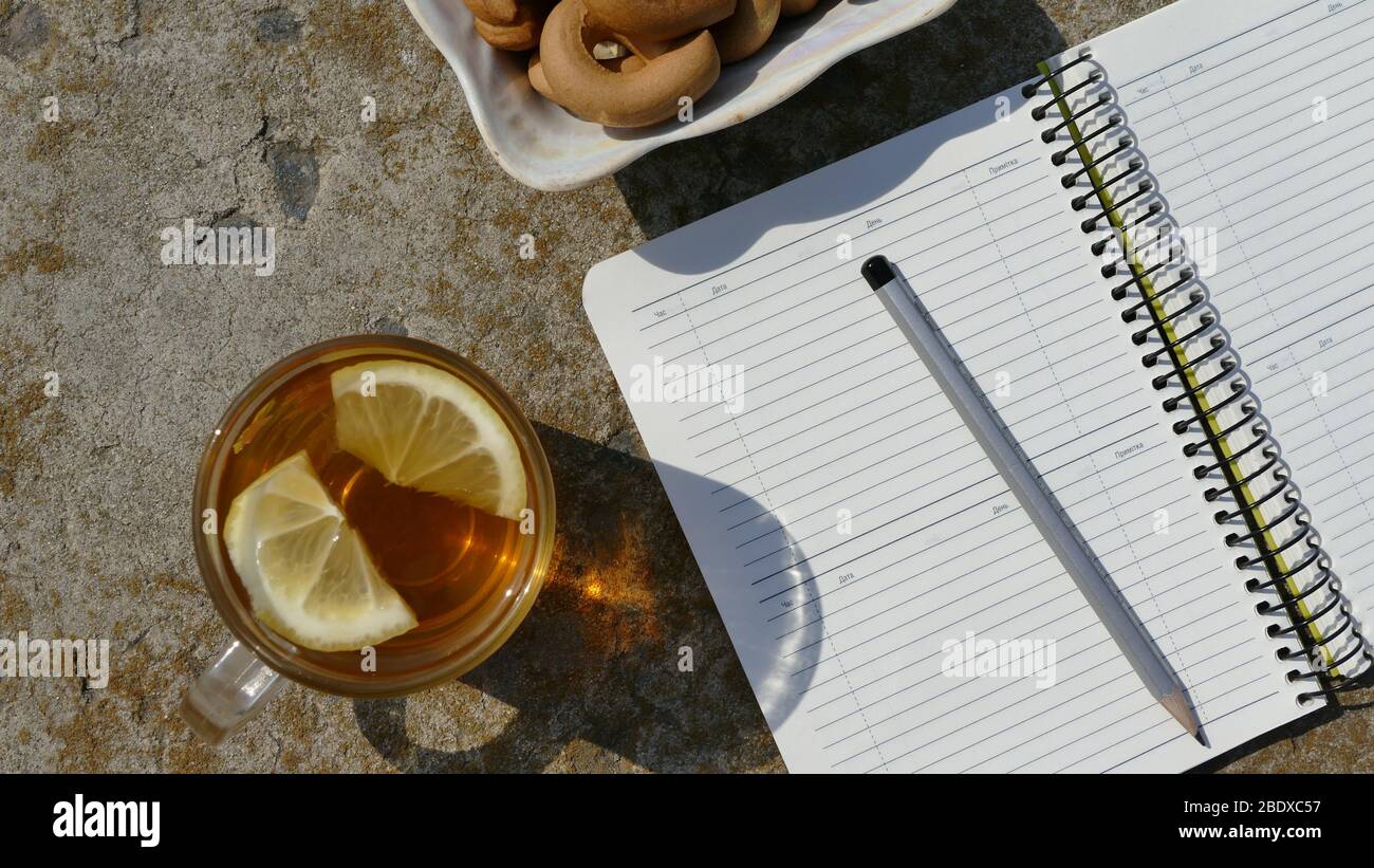 Working environment. Near the notebook is a cup of tea and a plate with bagels. Stock Photo