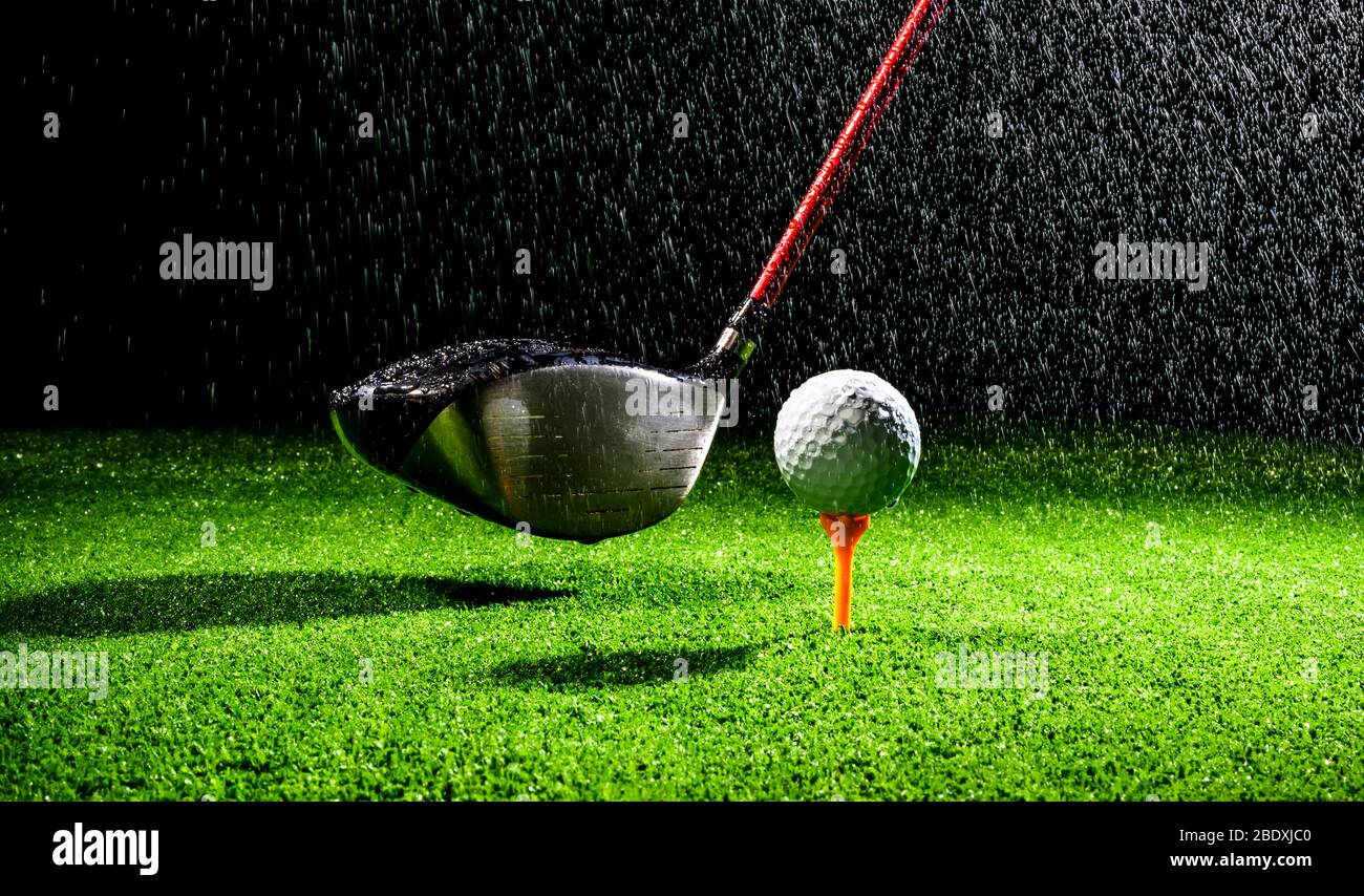 Horizontal close up shot of a golf ball and golf club driver wet from