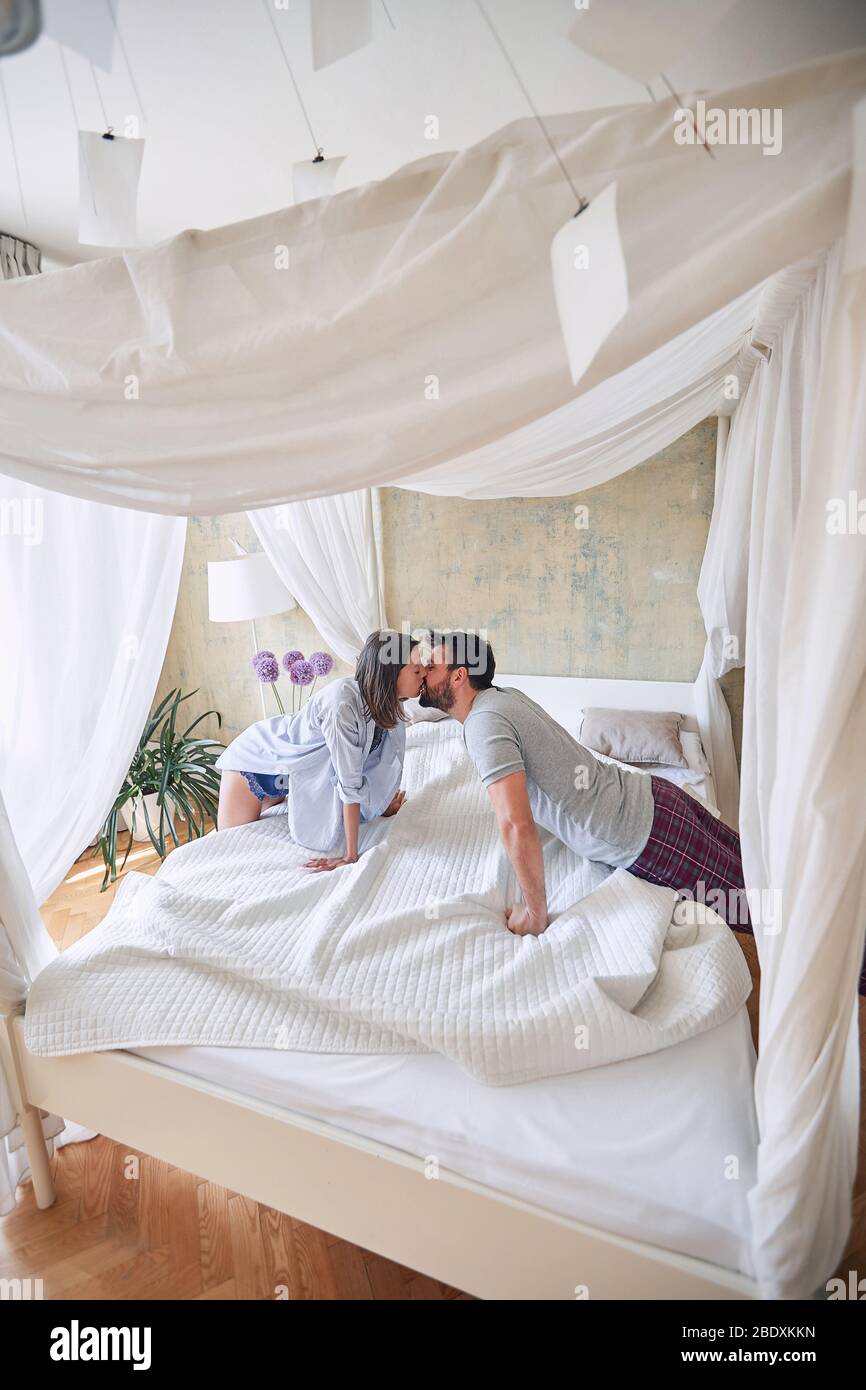 Loving young couple kissing in the morning while making the bed. Stock Photo