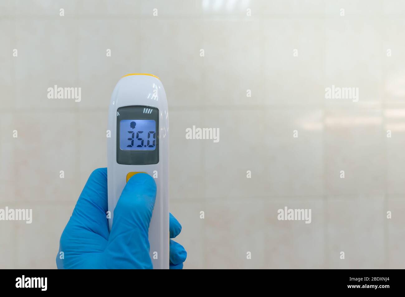 The doctor holds the infrared non-contact thermometer. The digital device displays the normal body temperature in degrees Celsius Stock Photo