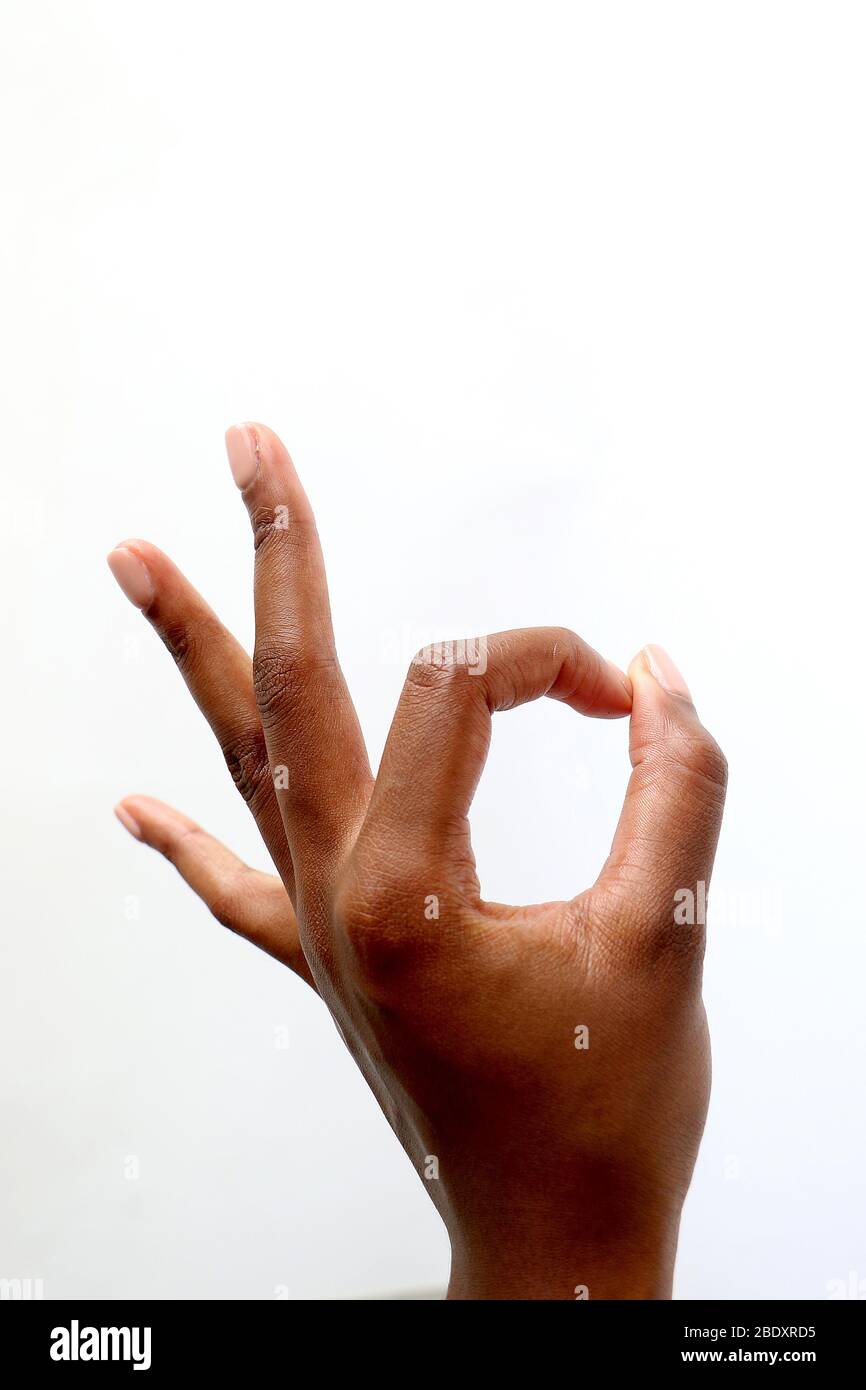 Isolated female black African Indian manicured hand gesturing okay against a white background Stock Photo