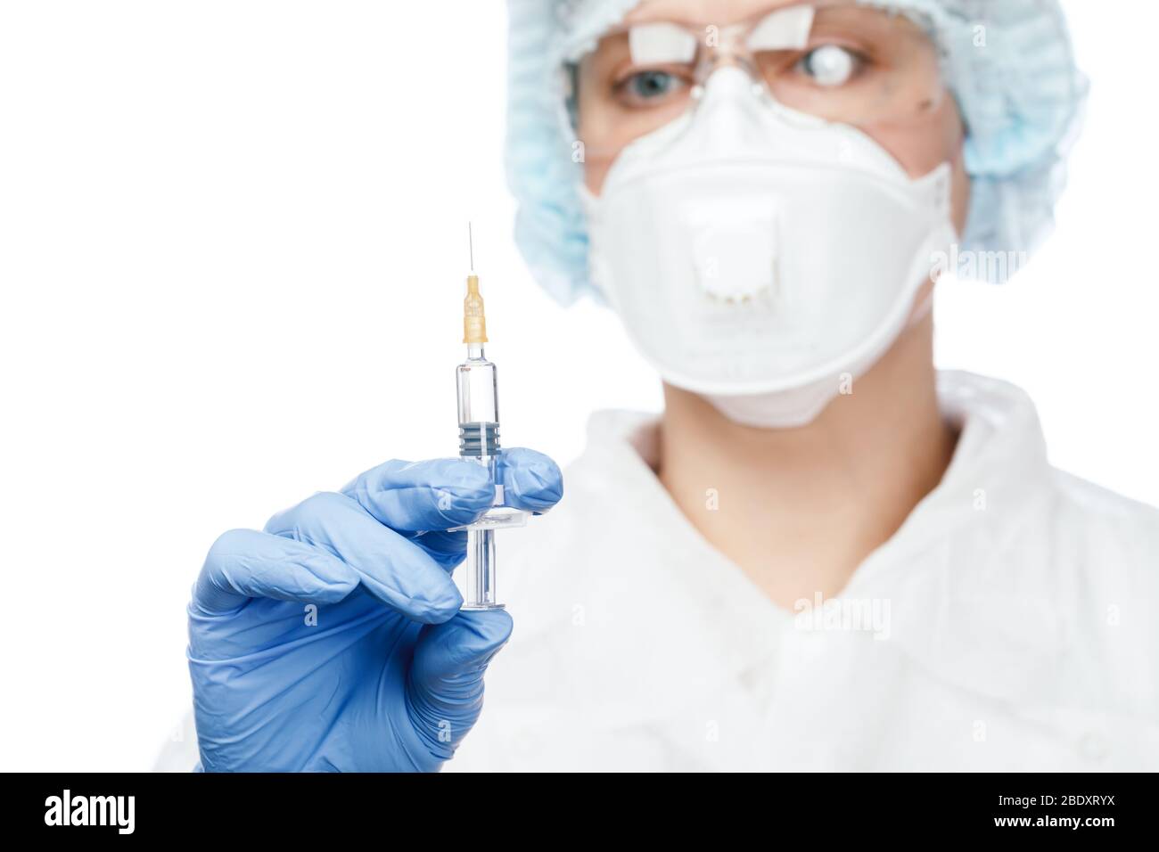 Close-up shot of doctor wearing protective suit, goggles and surgical mask holding syringe ready for injection Stock Photo