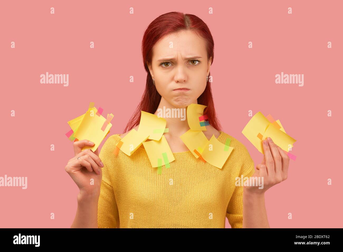 Serious looking young girl frown, covered with stickers listens information attentively. Young indignant, perturbed girl has long red hair, wears yell Stock Photo