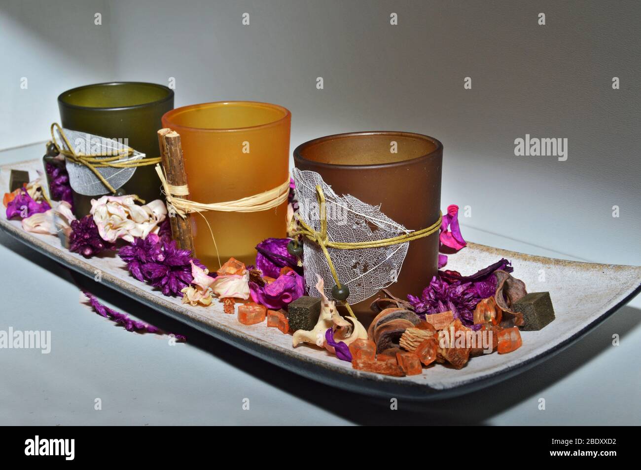 Closeup of display with dried flowers and aromatic candles on a platter, display poupourri with orange, purple and green theme, ideas for interior dec Stock Photo