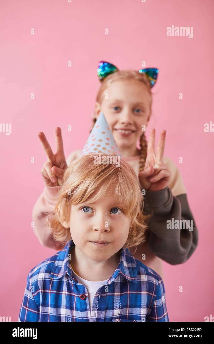 Portrait of two funny children posing at camera over pink background Stock Photo