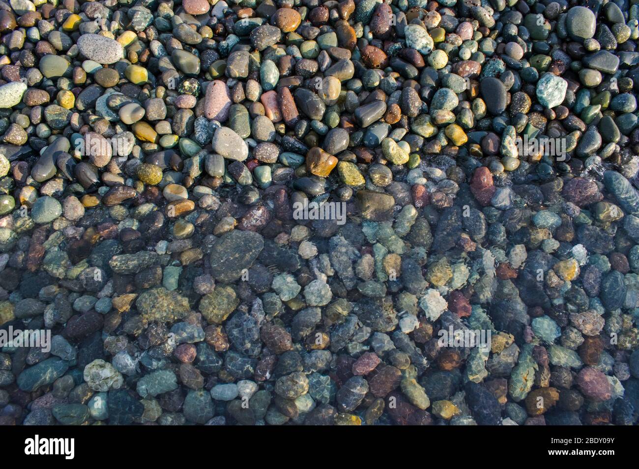 Colourful pebbles at under a very clear ocean water the sea shore Stock