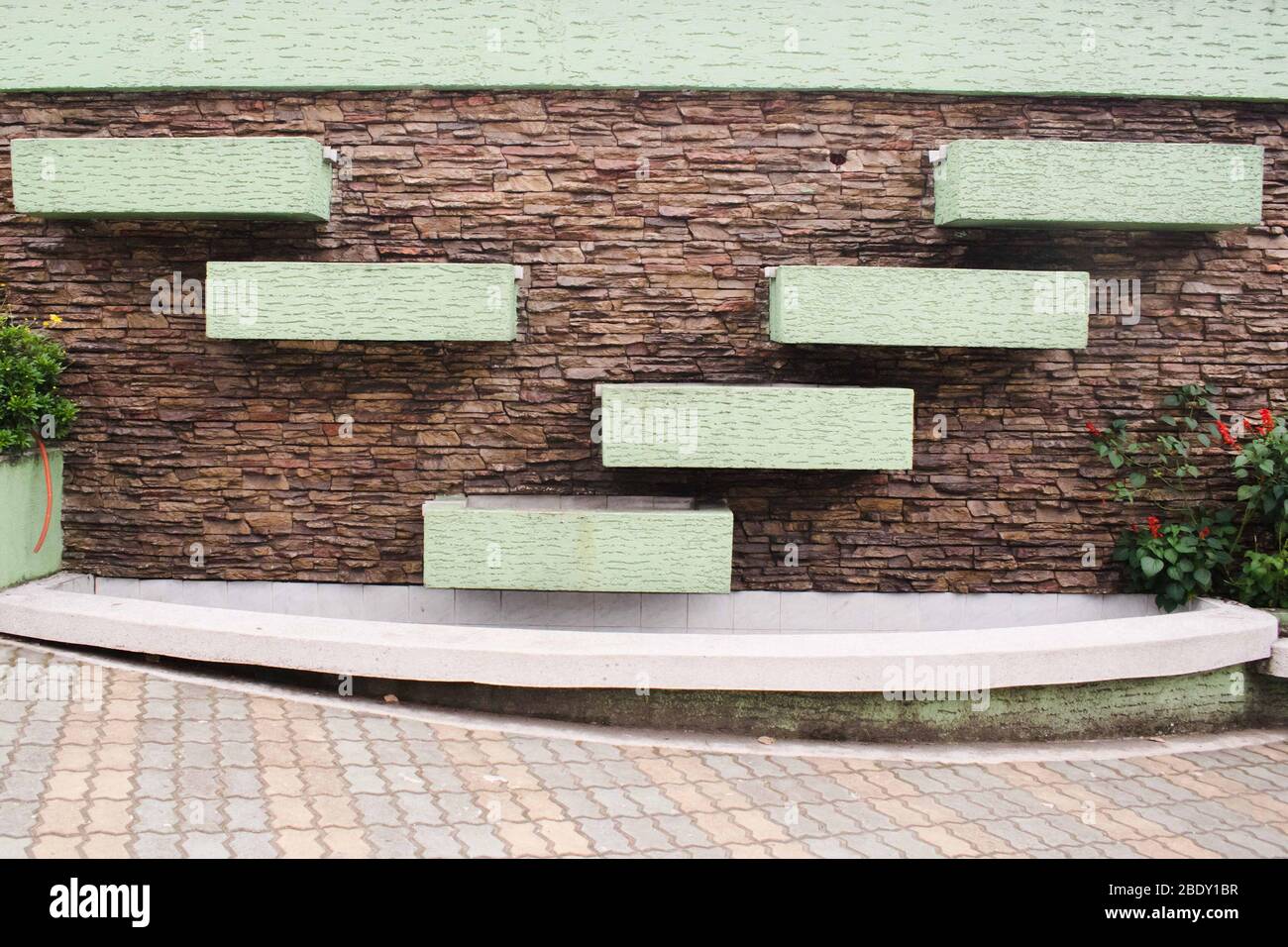 Brown brick wall with green painted rectangle arranged on a V pattern Stock Photo