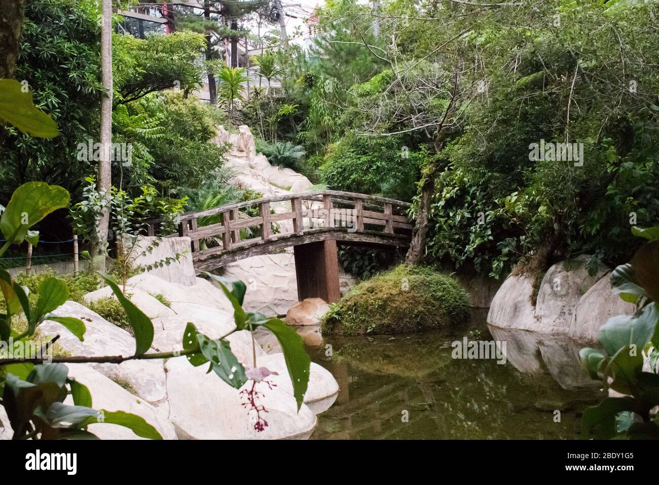 A small wooden bridge crossing a small lake at the zen garden Stock Photo