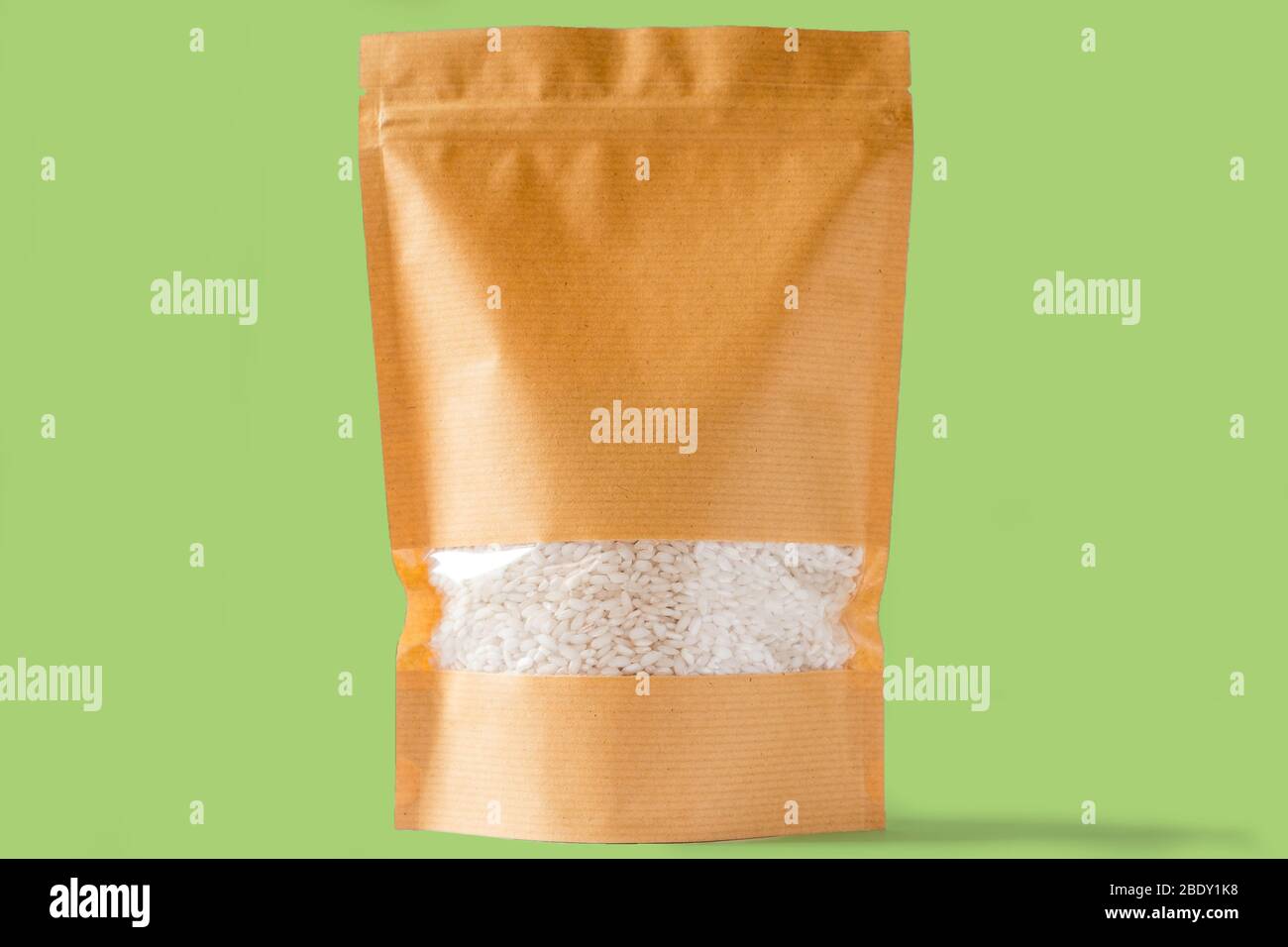 plain brown paper doy pack stand up bio pouch with window on white green background filled with rice Stock Photo