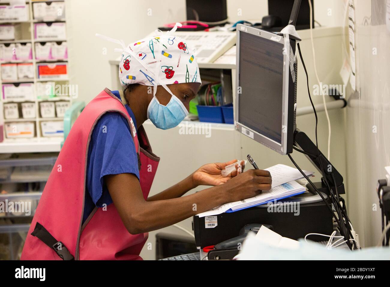 An NHS Nurse records notes on a patient during surgery in an NHS