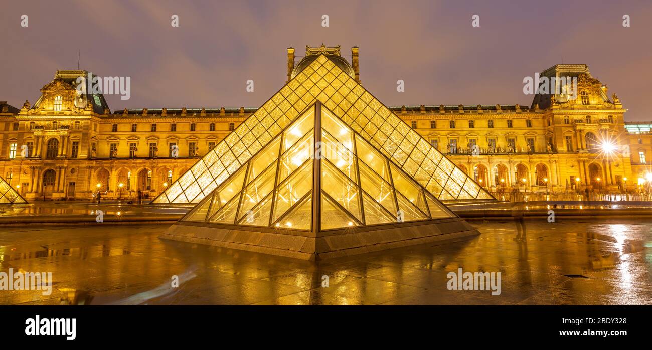 View of famous Louvre Museum with Louvre Pyramid at Night Stock Photo