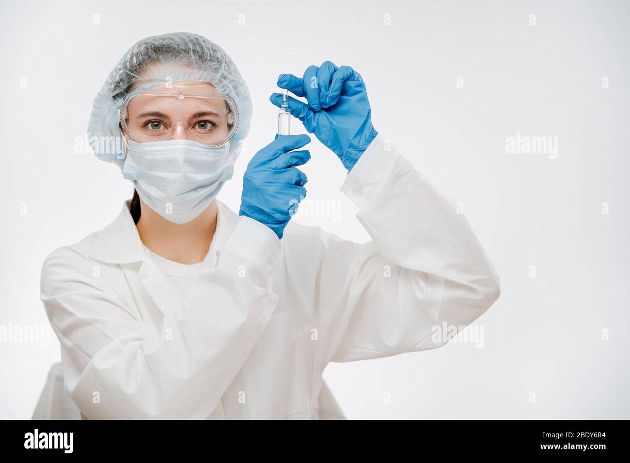 woman in mask with gloves holding ampule with medicine to cure for coronavirus Stock Photo