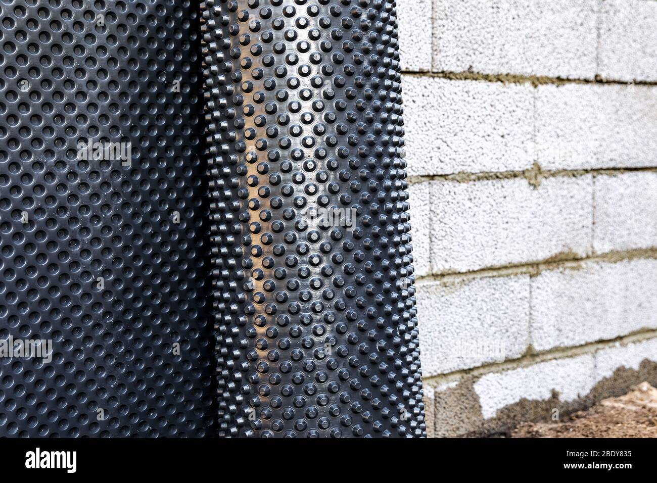 basement wall waterproofing - installing dimple geomembrane Stock Photo