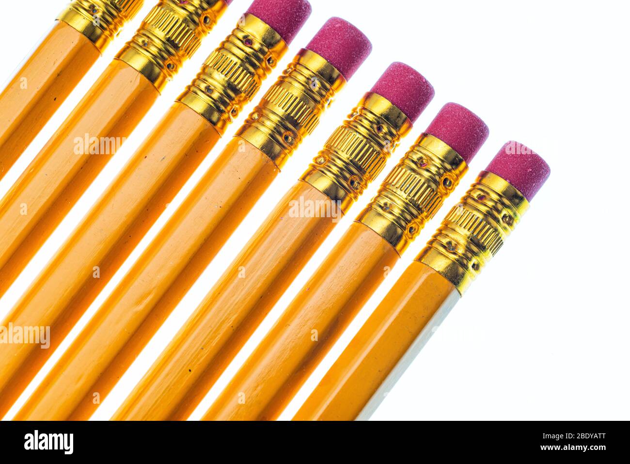 Horizontal closeup shot of the eraser end of seven slanted pencils. Cropped. White background