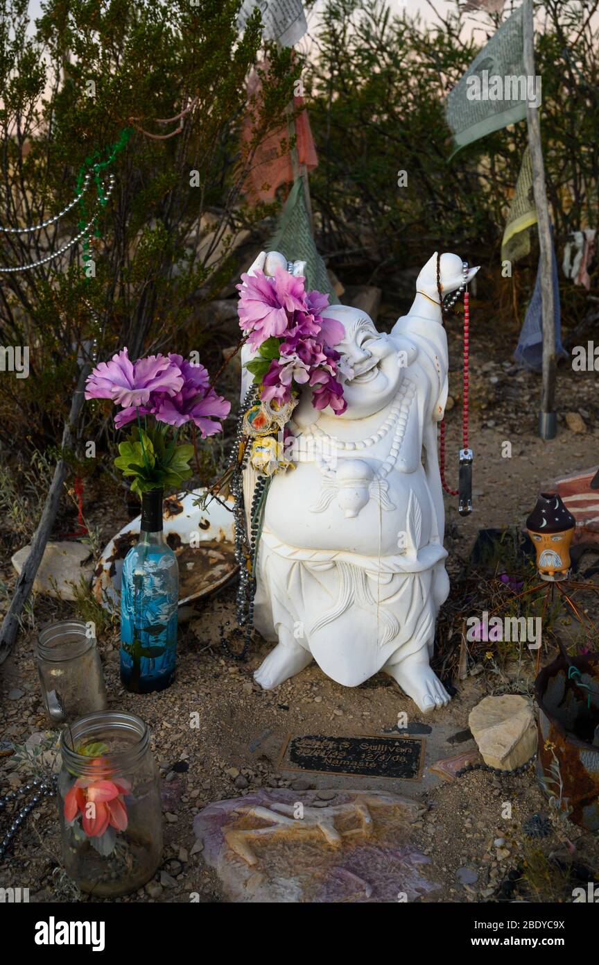 A small happy Buddha statue marks this grave in the Terlingua Cemetery in West Texas, where the graves are marked by handmade embellishments. Stock Photo