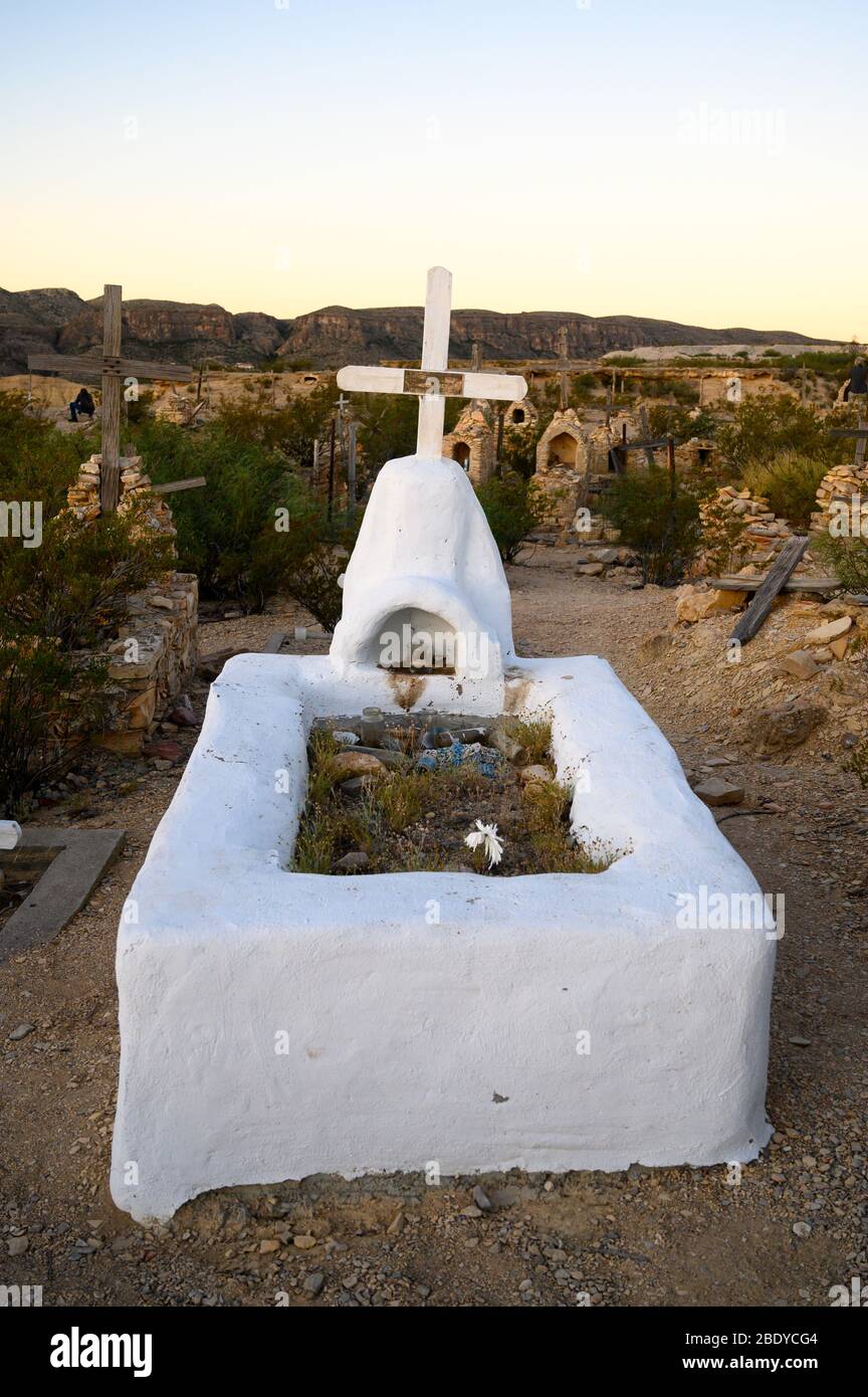 This white adobe grave has a white cross and small shrine in the Terlingua Cemetery in West Texas, where the graves are marked by handmade embellishme Stock Photo