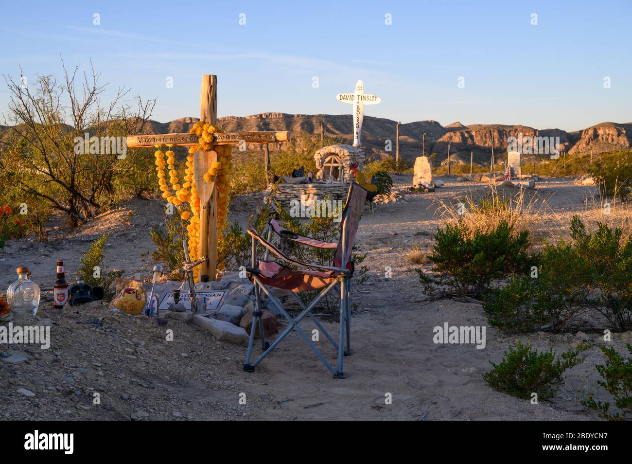 A camping chair sits by a grave in the Terlingua Cemetery in West Texas, where the graves are marked by handmade embellishments. Stock Photo