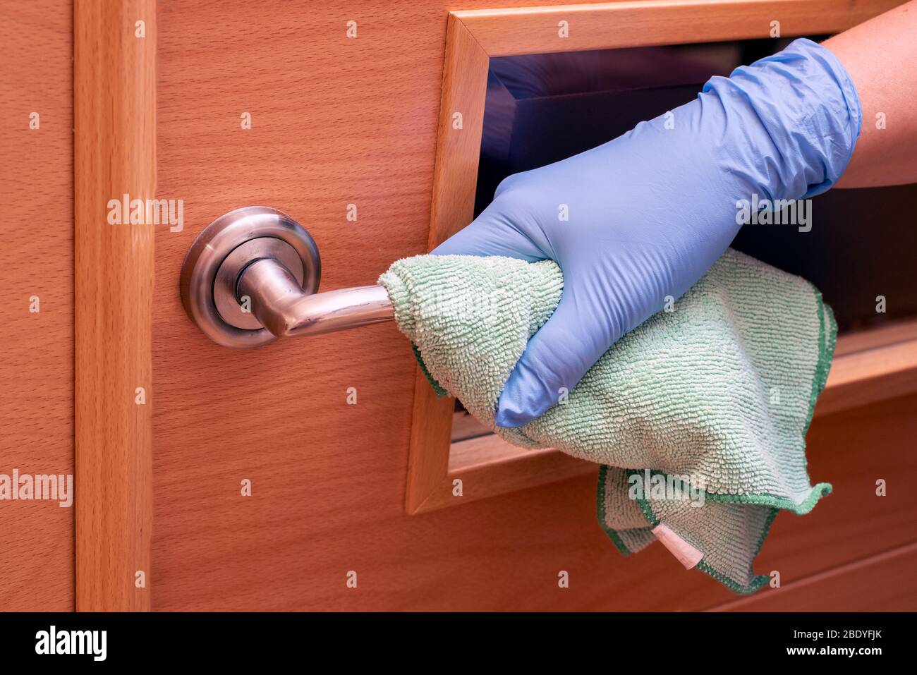 Hand cleaning and disinfecting a door handle Stock Photo