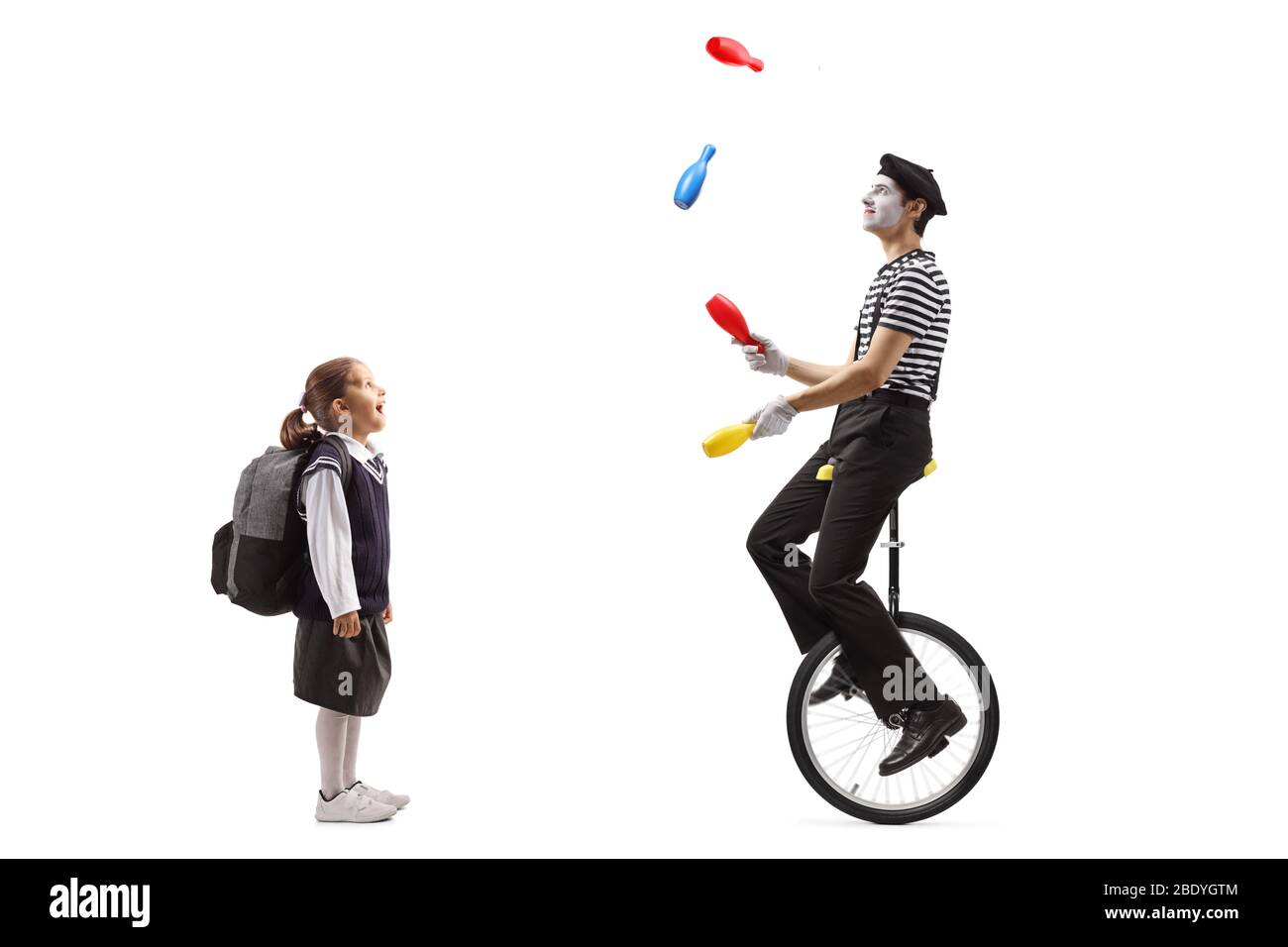 Full length profile shot of a schoolgirl watching a clown juggling and ...