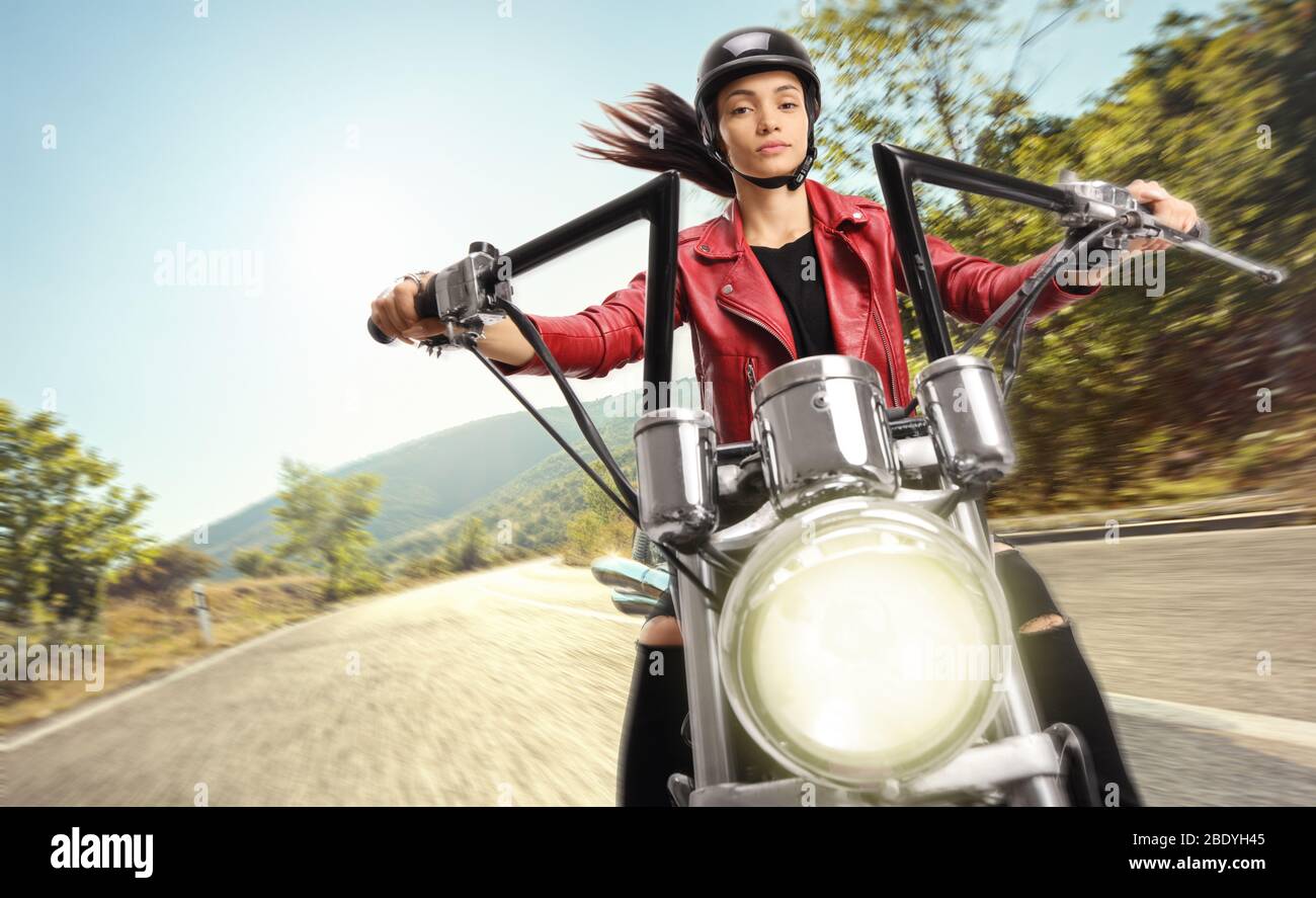 Young female biker riding a custom motorbike on the road Stock Photo