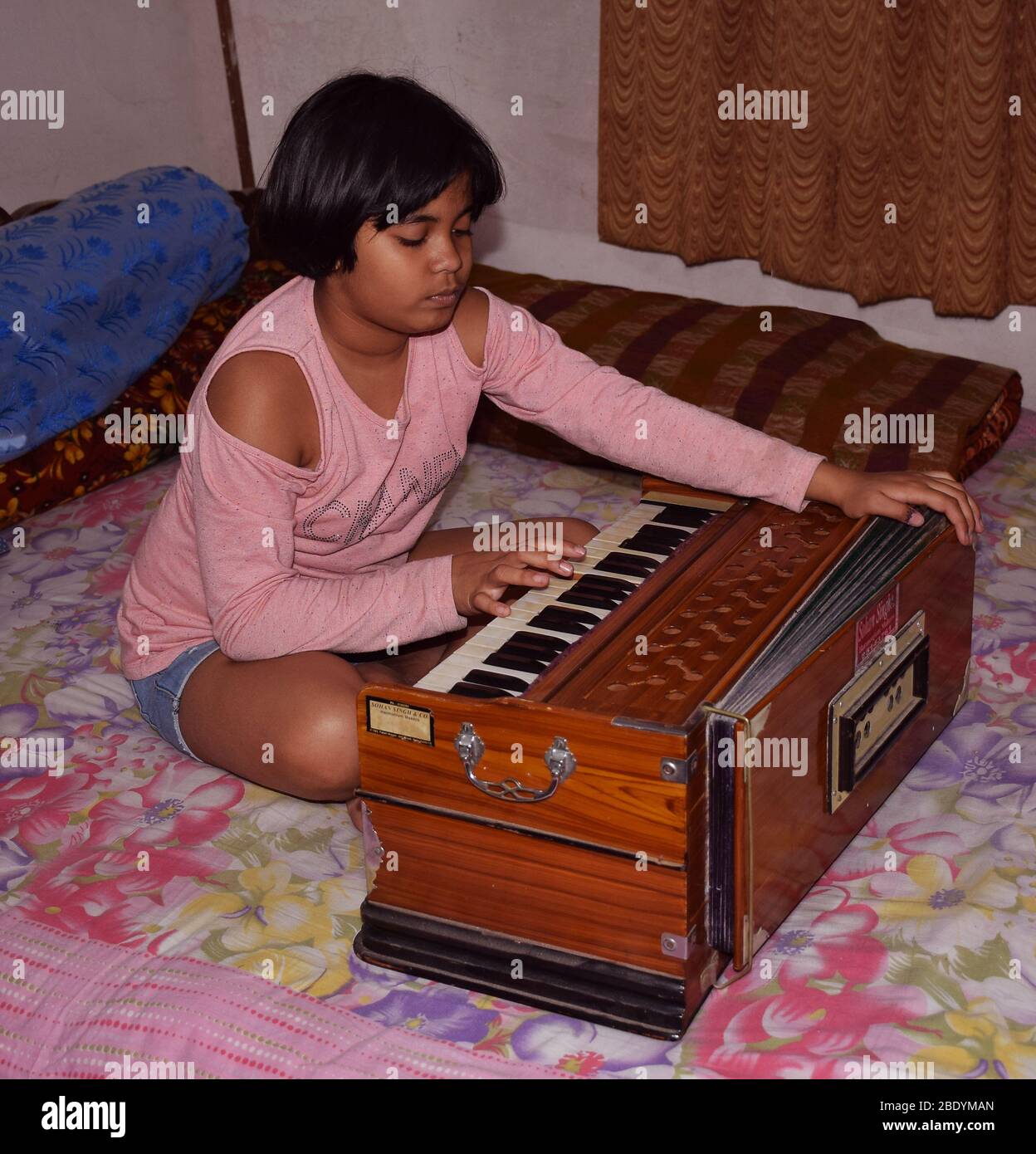 An Indian Child playing musical instrument Harmonium Stock Photo