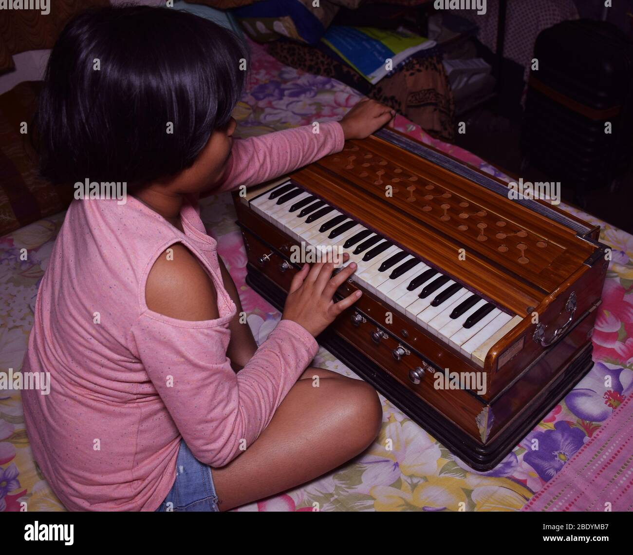 Back shot of an Indian girl playing Harmonium Stock Photo