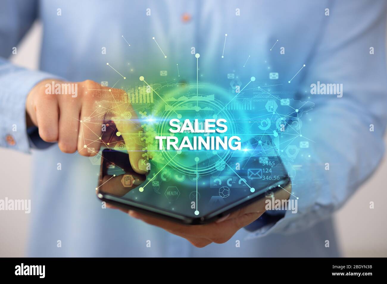 Businessman holding a foldable smartphone with SALES TRAINING inscription, new business concept Stock Photo