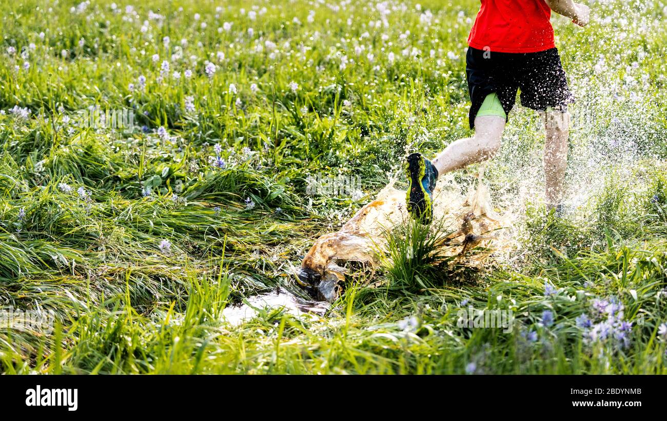 A man runs through a puddle in late spring in MT. Stock Photo