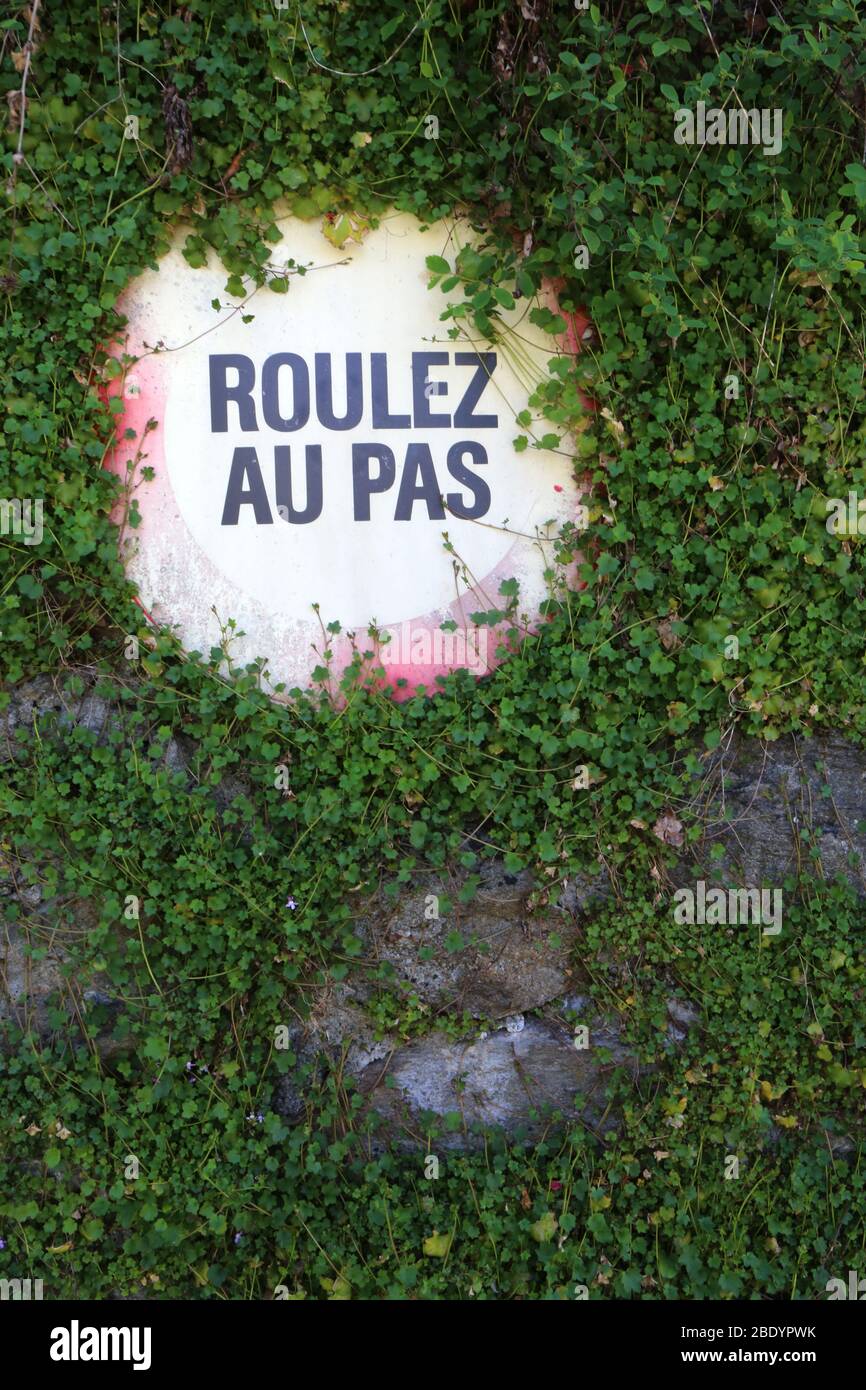 Roulez au pas. Panneau sur un mur recouvert de lierre. Saint-Gervais-les-Bains. Haute-Savoie. France. Stock Photo