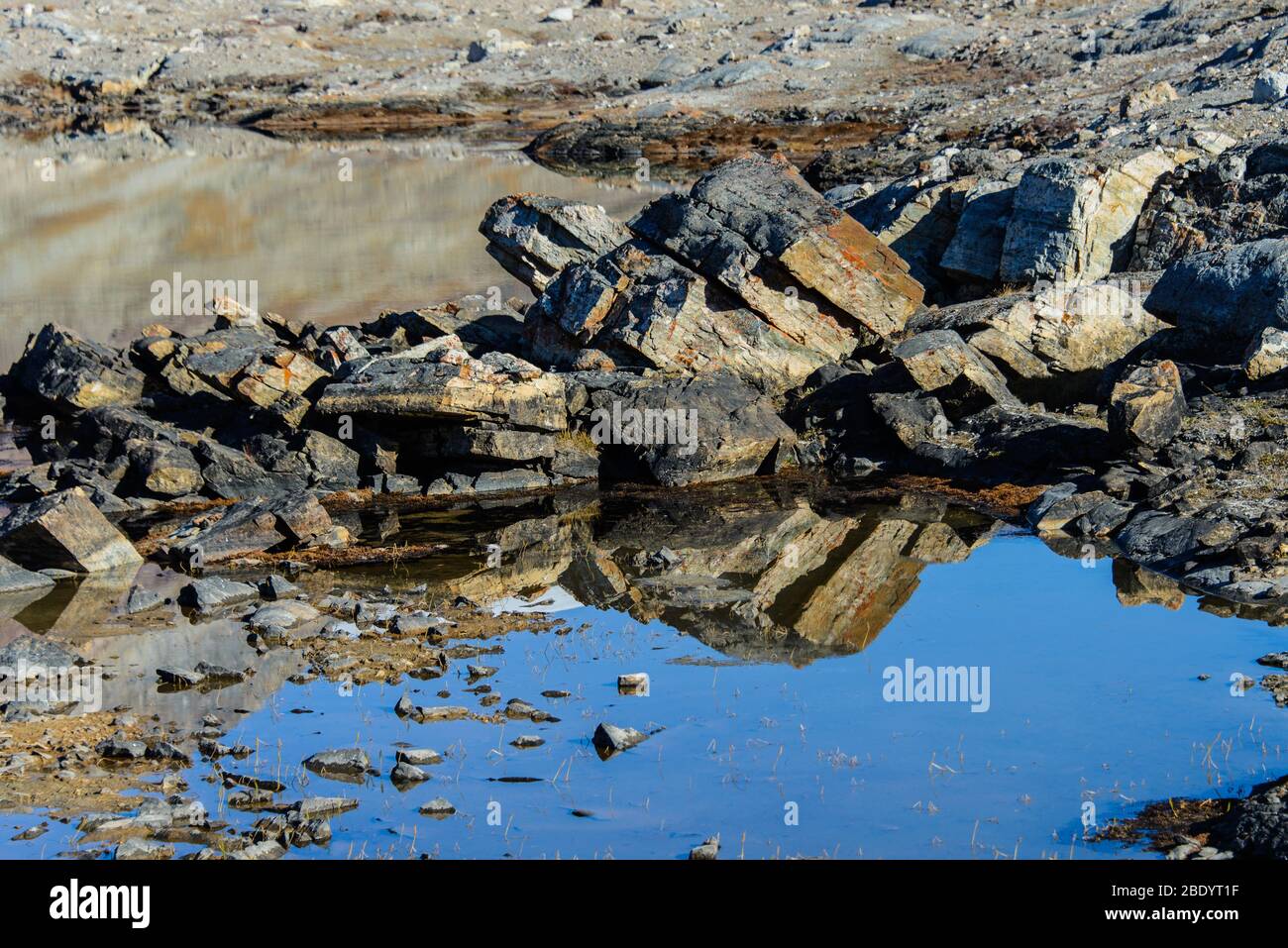 Greenland Coastal Rocks Greenland landscape with beautiful coloured rocks. Reflection in water ...