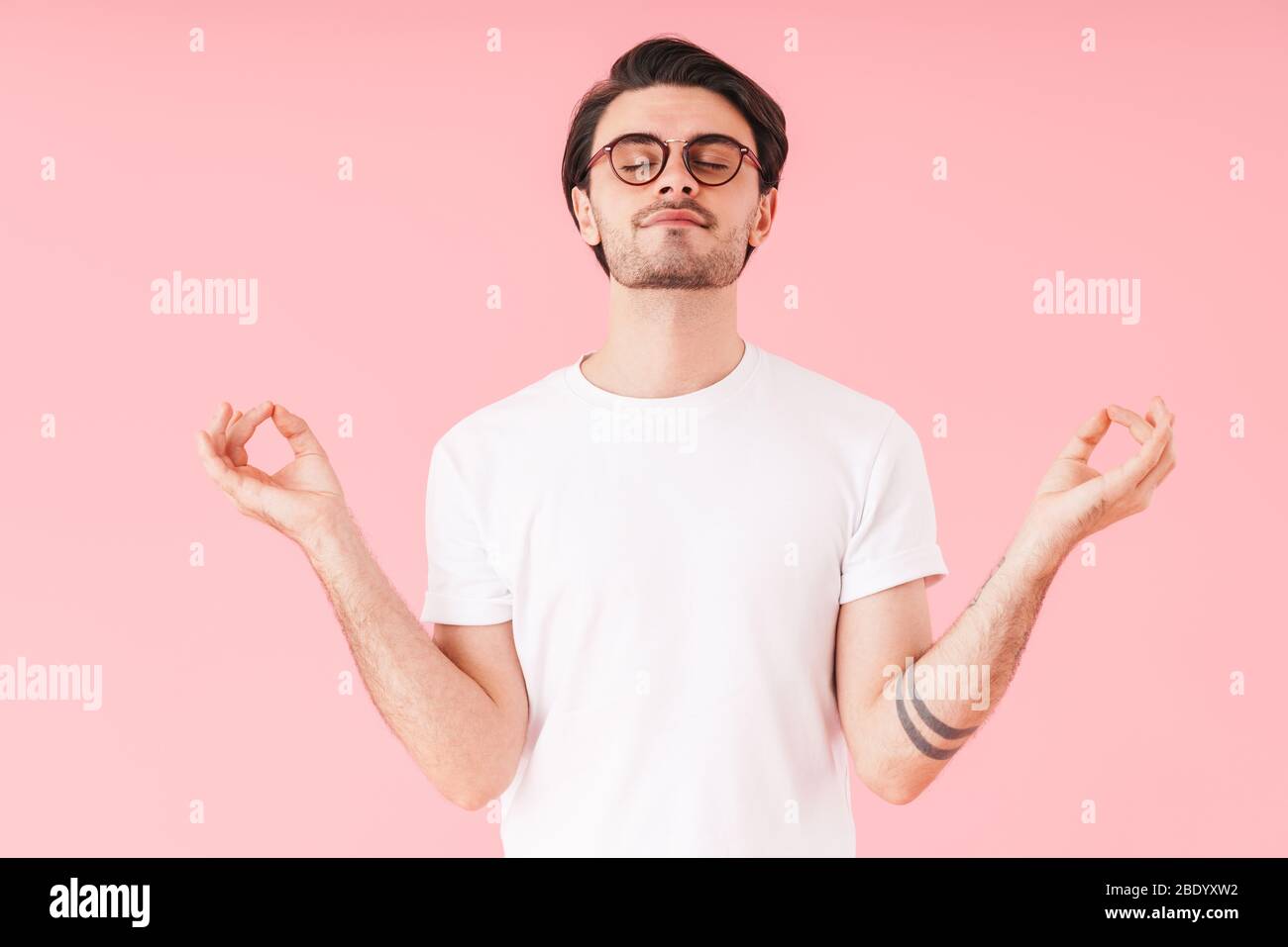 Image of young calm man wearing eyeglasses meditating with eyes closed ...