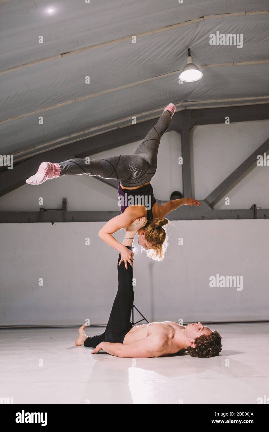 Theme sport and a healthy lifestyle. Acrobatics and acroyoga. Young sporty couple practicing acroyoga handstand. Male and female acrobats doing Stock Photo