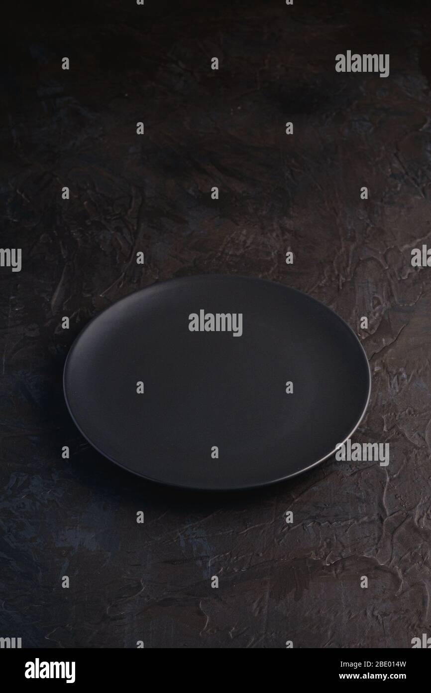 Empty black plate on dark textured background, angle view Stock Photo