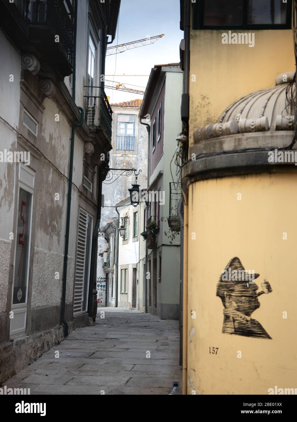 Typical traditional old narrow street of Viana Do Castelo Northern Portugal with little street art of a head of man smoking a pipe Stock Photo